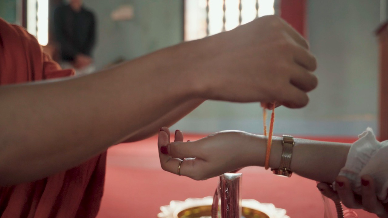Monk tying red blessing string on wrist